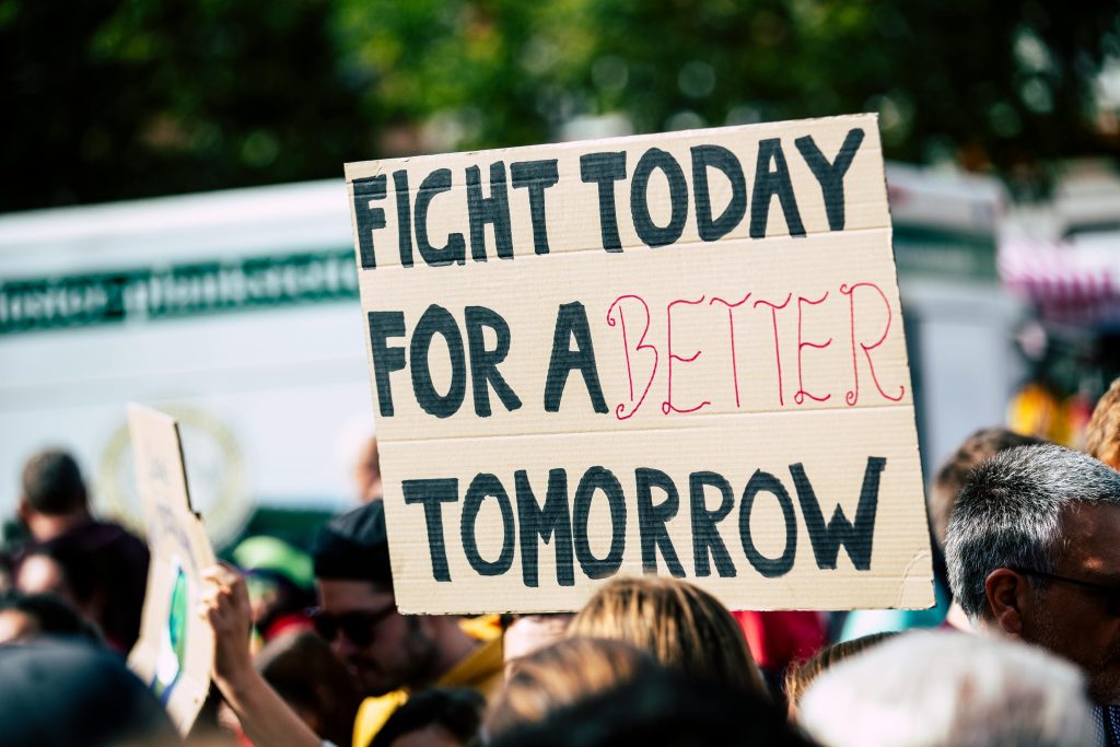 pexels photo 2990644 2990644 Crowd holding a protest sign with 'Fight Today for a Better Tomorrow', outdoors and during the day.